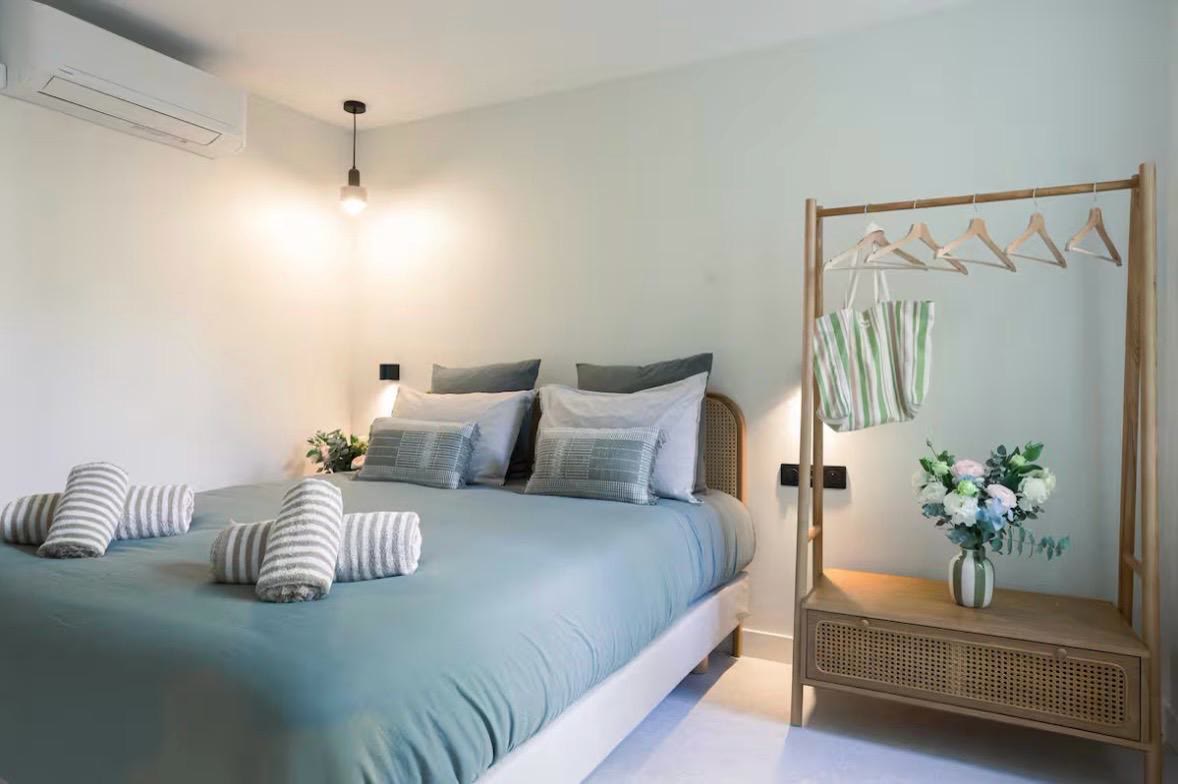Chambre habillée de vert sauge, penderie ouverte en bois et bouquet frais au chevet.