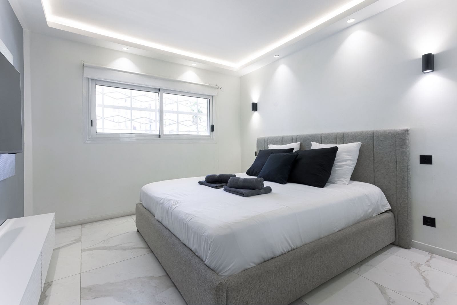 Chambre paisible, literie immaculée et appliques murales design.